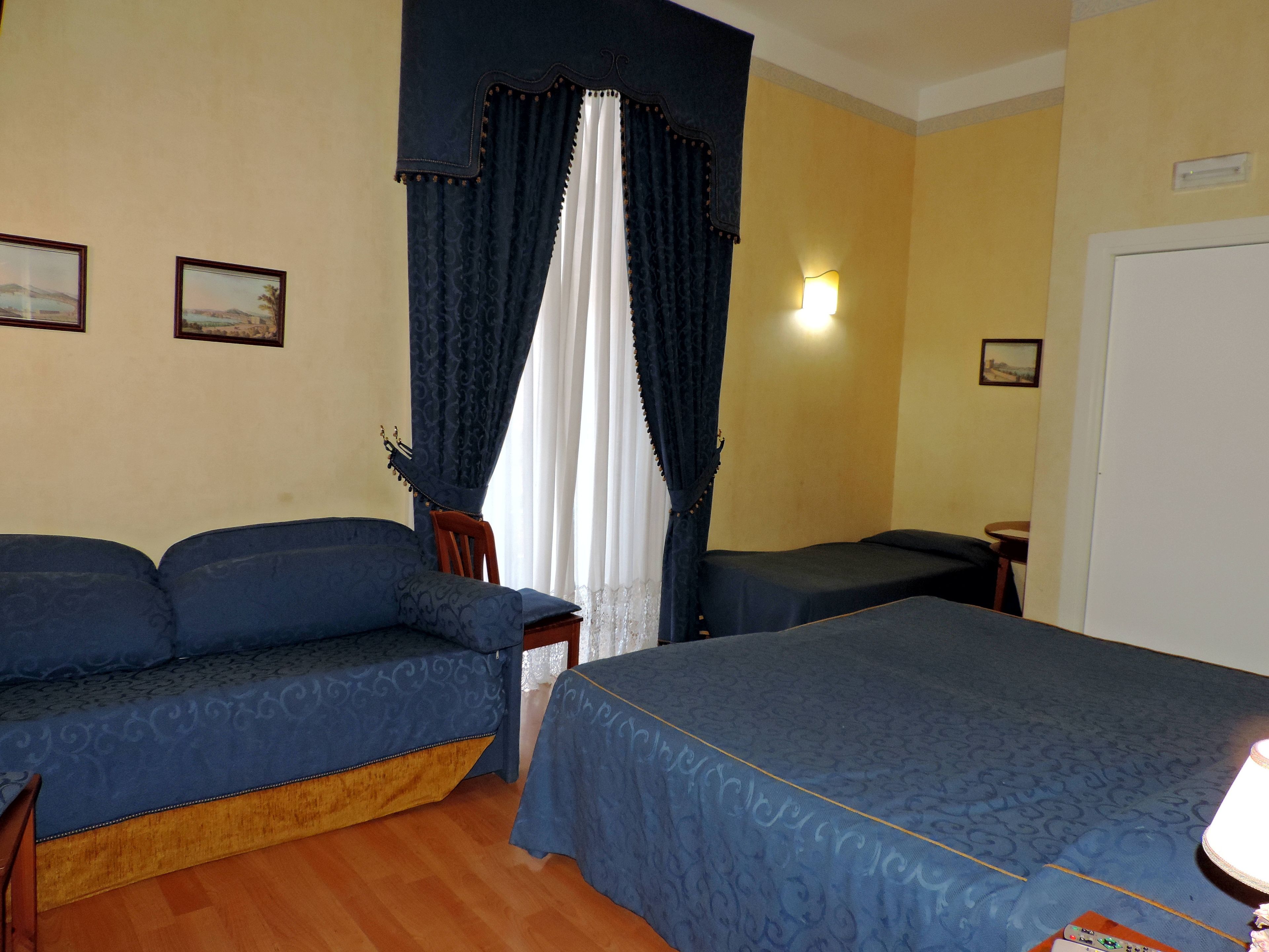 A hotel room with a bed, a sofa, a chair, and a small table.