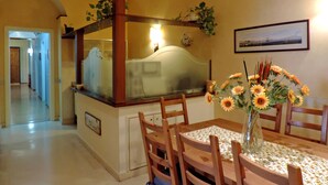 Un comedor con una mesa de madera, sillas, un jarrón de flores y un reloj en la pared.