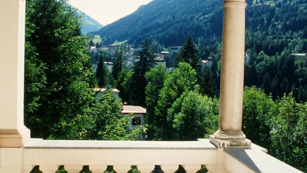 A balcony with wicker chairs and a table, overlooking a mountainous landscape. - Villa Excelsior Hotel Kurhaus (Bad Gastein)