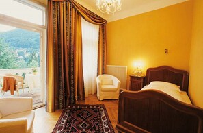 Une chambre avec un lit, une chaise, un radiateur et une vue sur l’extérieur.
