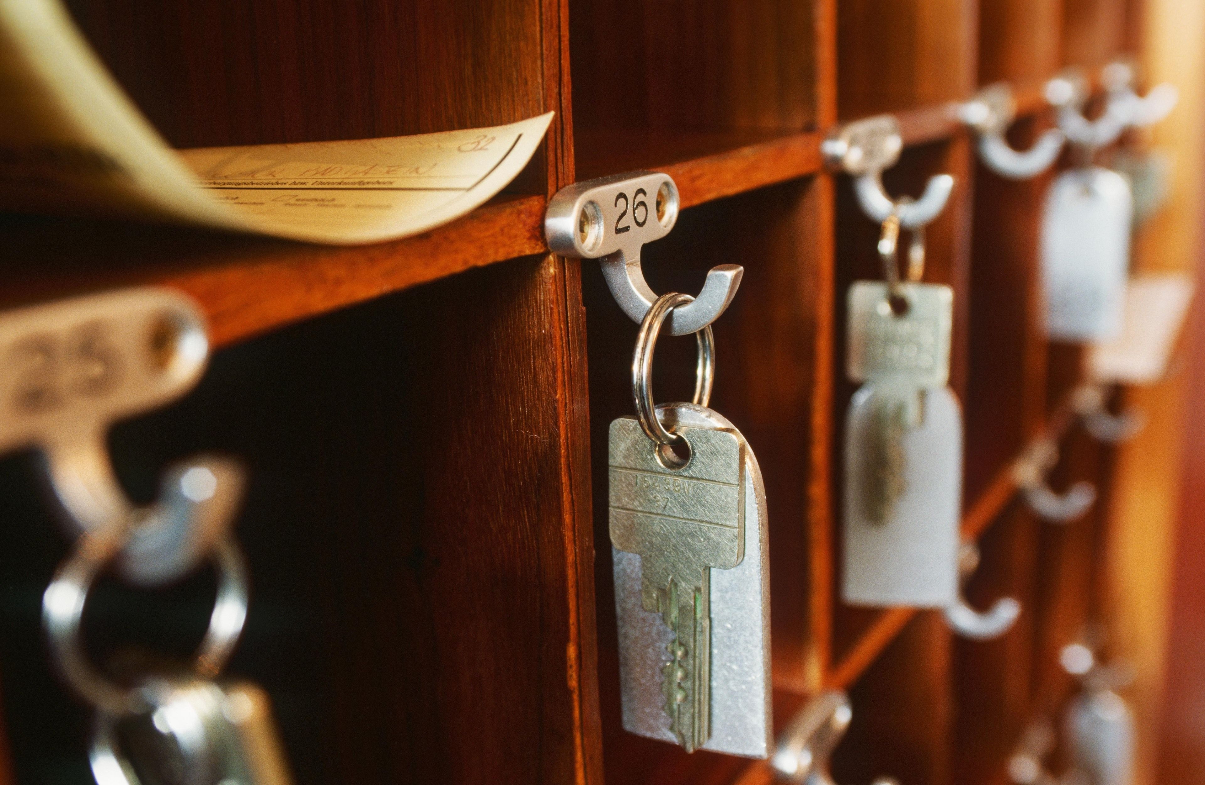 A close-up of a wooden door with numbered metal key hooks, each holding a key.