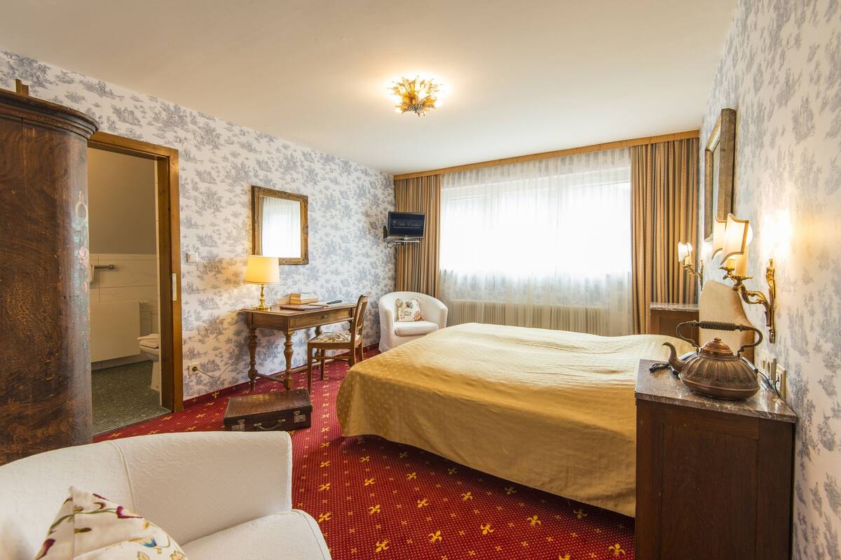Une chambre d’hôtel comprenant un lit, un bureau, une chaise, une armoire et un téléviseur.