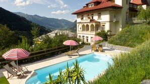 A large building with a swimming pool, surrounded by lush greenery and mountains. - Villa Excelsior Hotel Kurhaus (Bad Gastein)