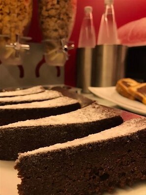 A slice of chocolate cake with powdered sugar on a plate.