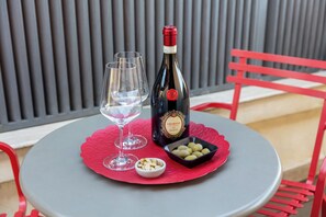 A table with a bottle of wine, two glasses, and a small bowl of nuts on a red placemat.