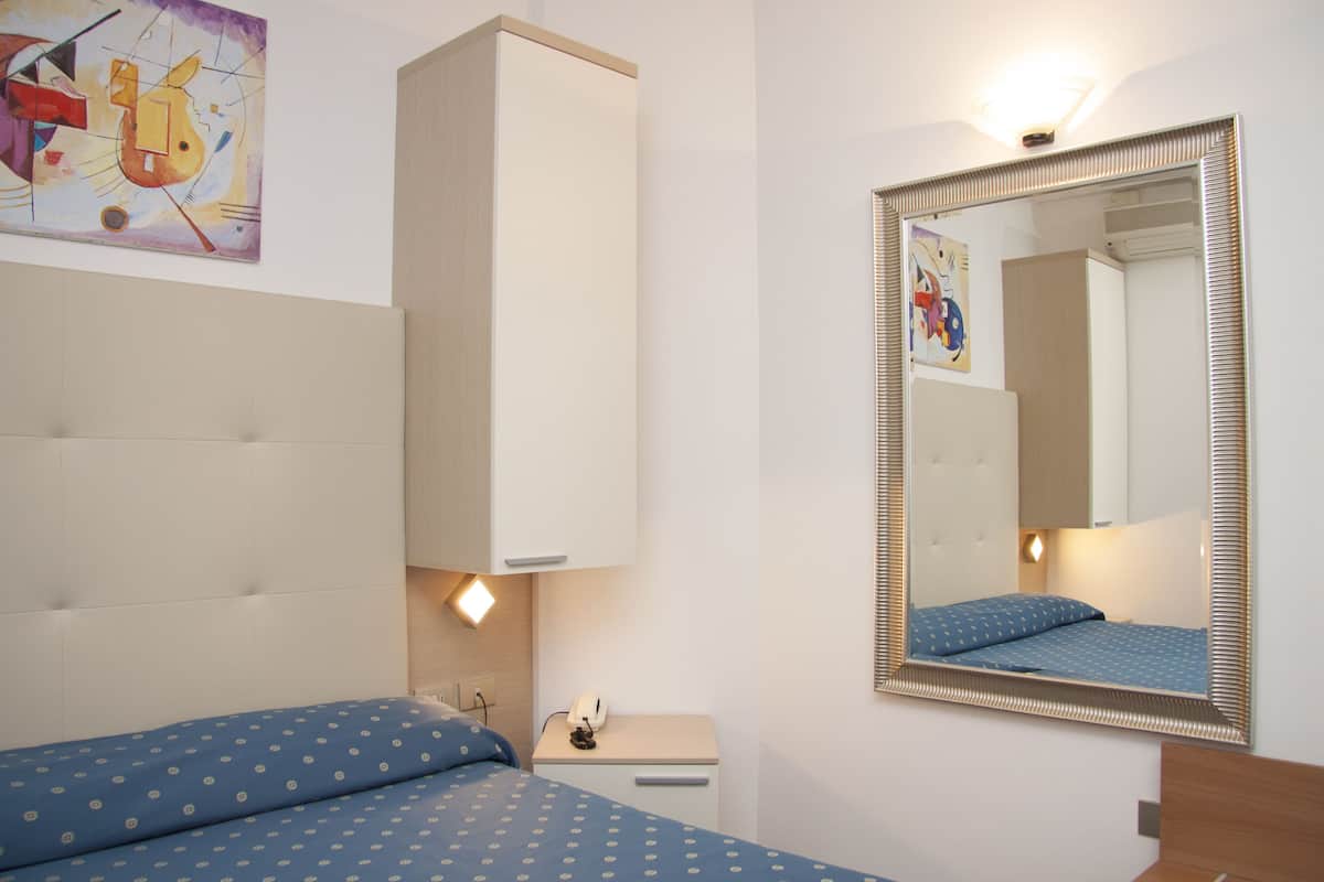 A bedroom with a bed, bedside table, and a mirror.