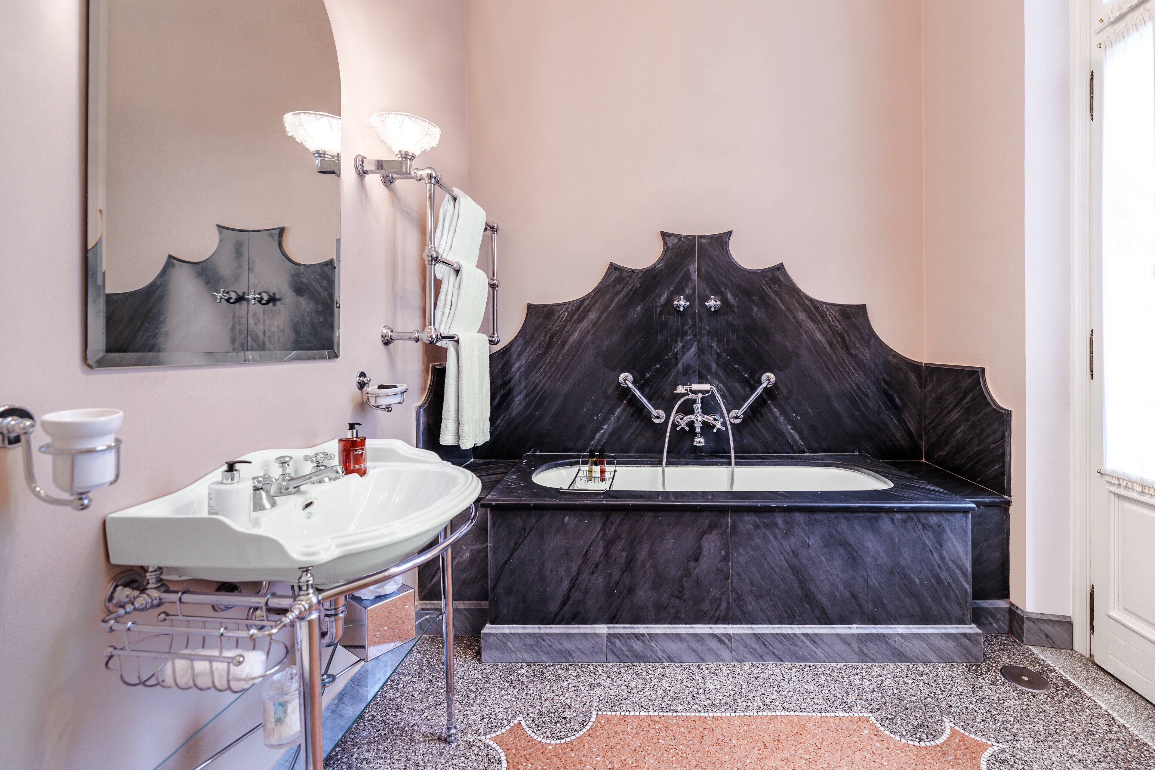 A bathroom with a marble sink, a bathtub, and a large mirror.