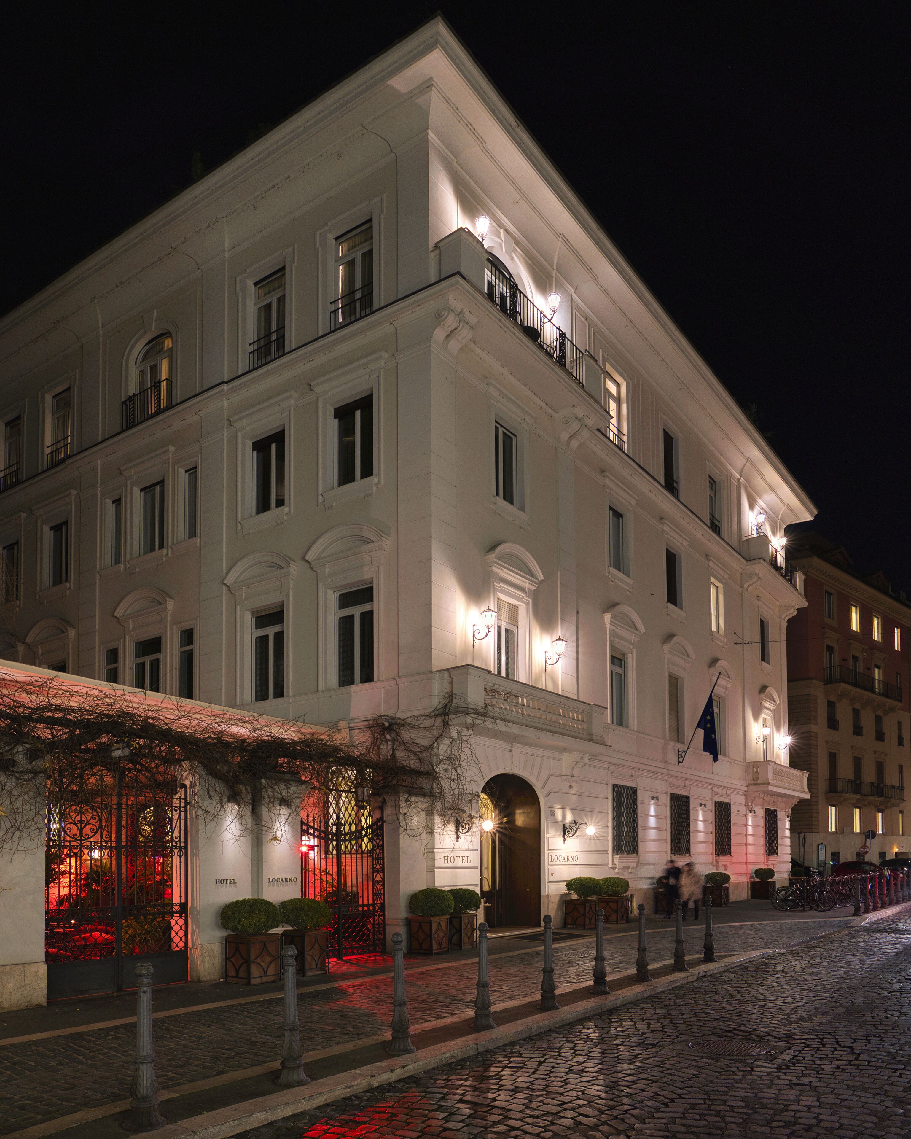 A historic hotel with a classic facade, multiple balconies, and a well-lit entrance.
