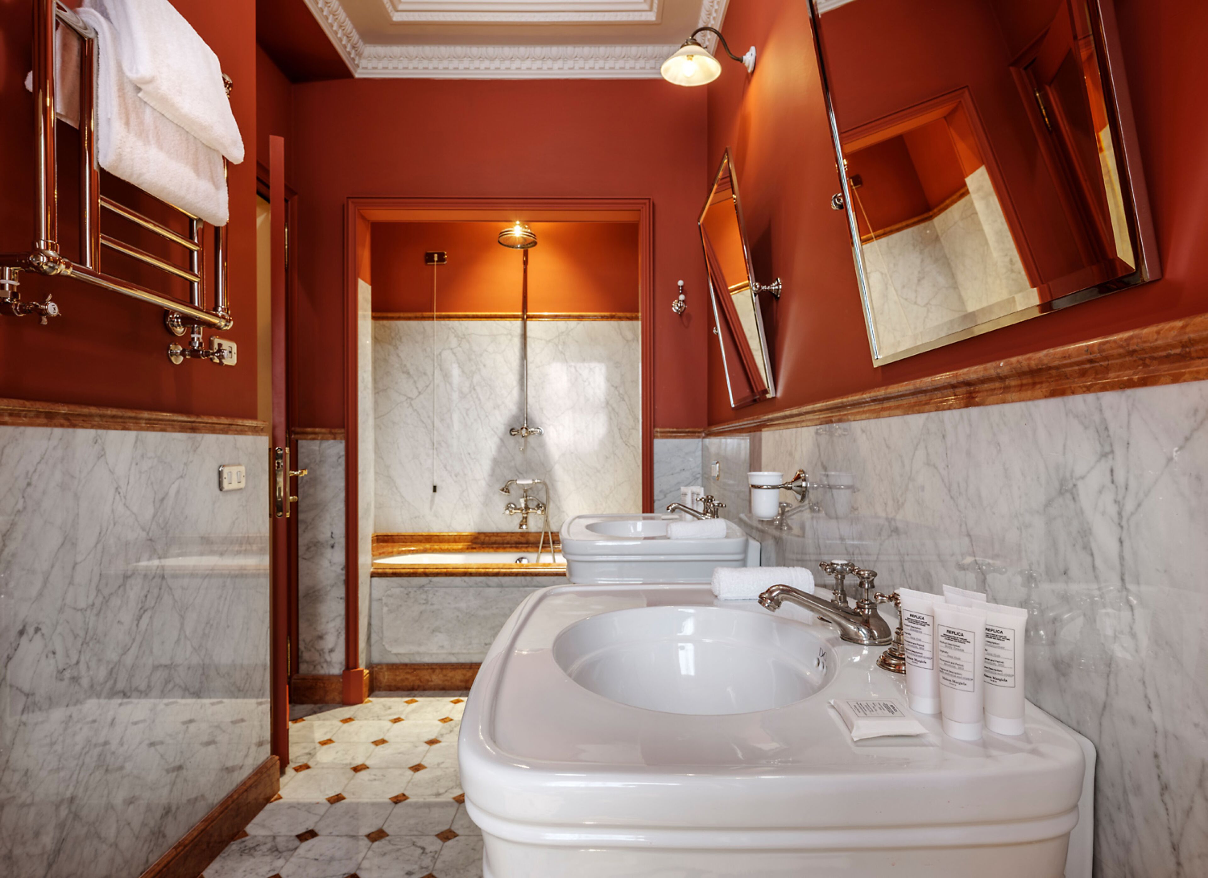 A bathroom with a large sink, two mirrors, a shower, and a towel rack.