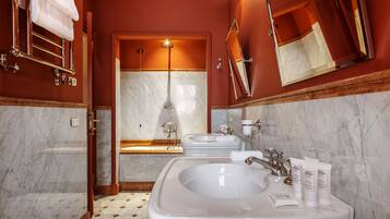 A bathroom with a large sink, two mirrors, a shower, and a towel rack.