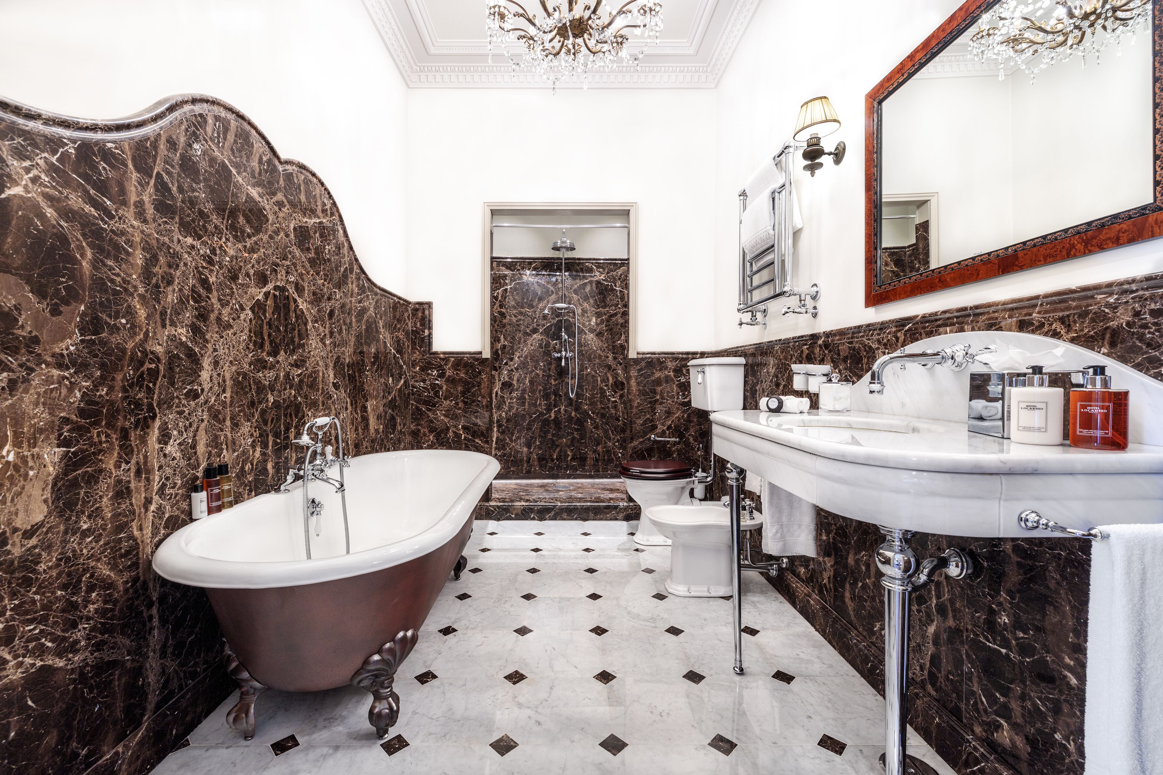 A bathroom with a freestanding bathtub, a toilet, and a sink with a mirror above it.
