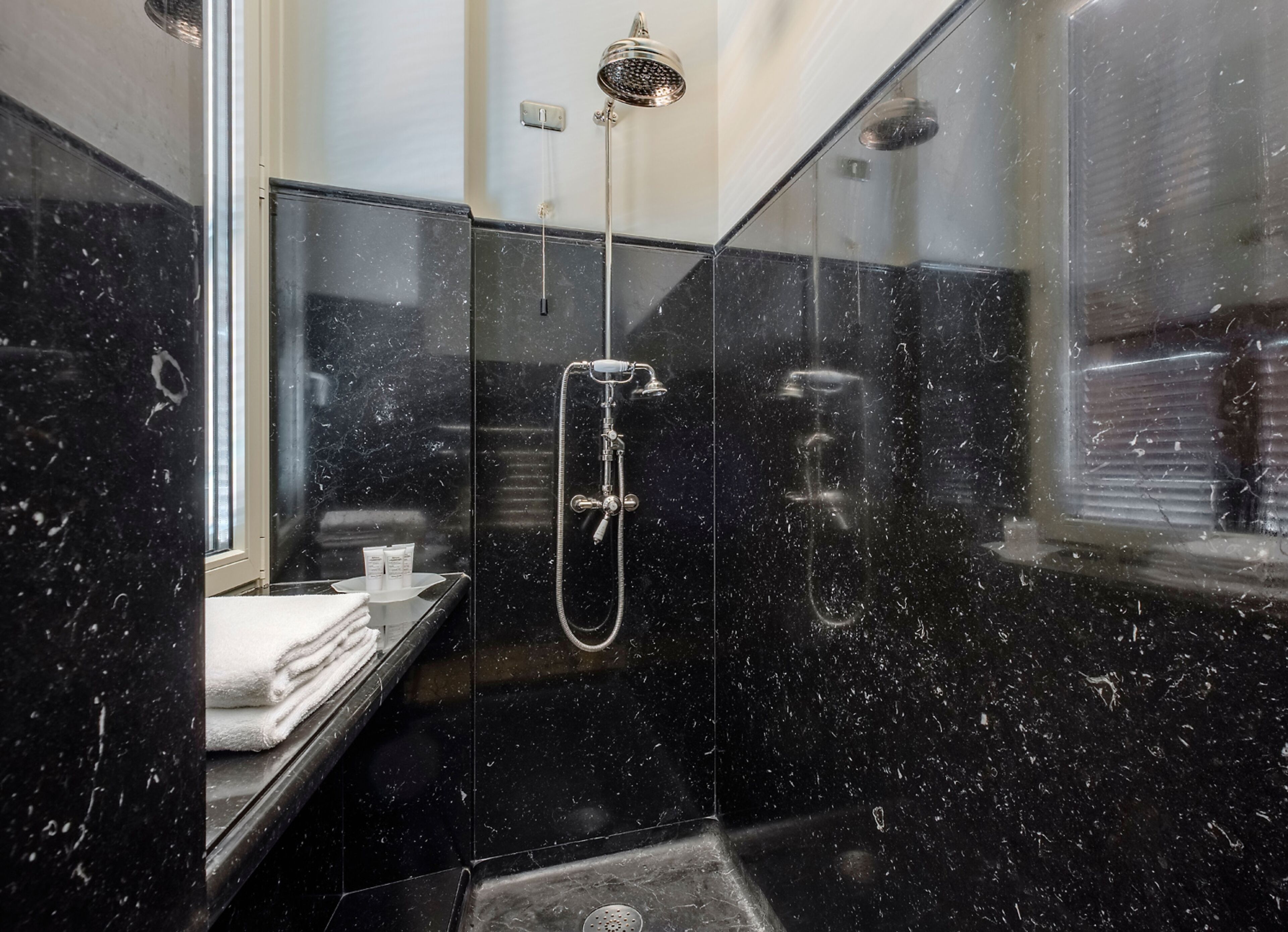 Ein modernes Badezimmer mit einer gläsernen Dusche, einem Waschtisch mit Spiegel und einem Fenster.