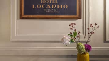 Póster enmarco del Hotel Locarno en Roma, con un florero sobre una mesa.