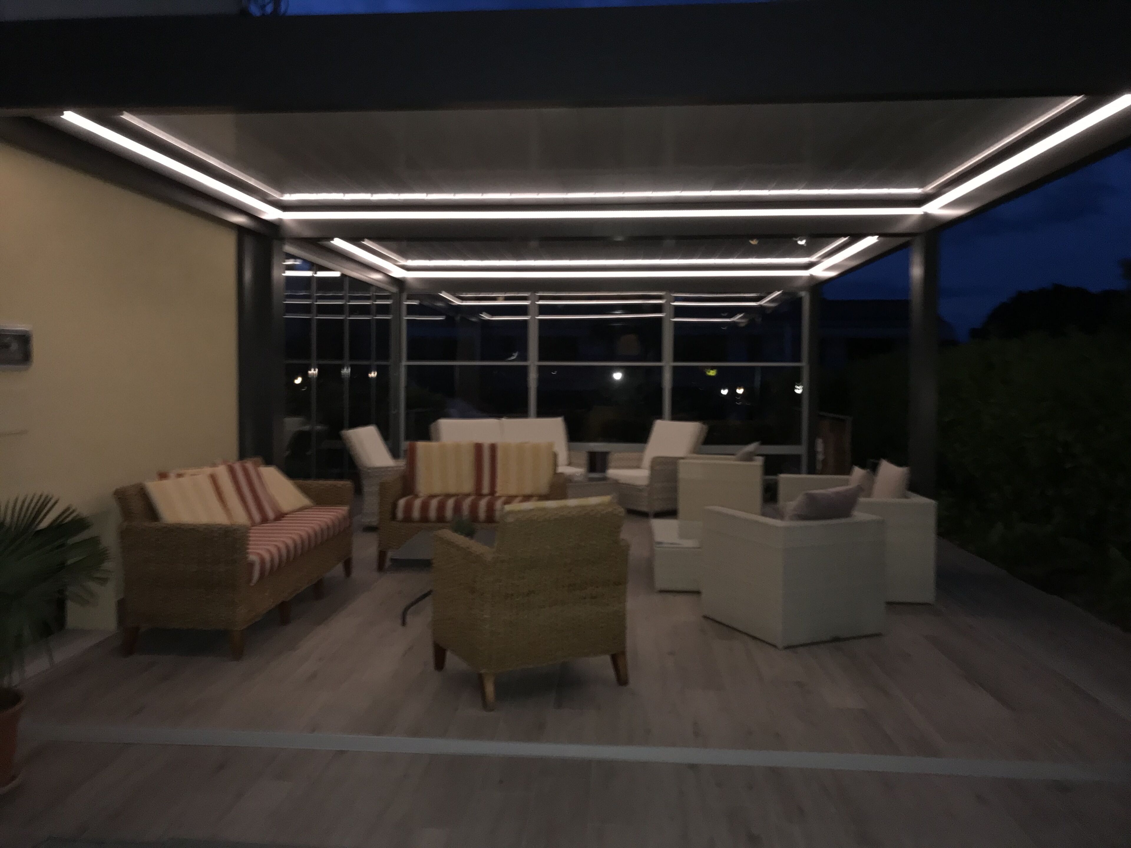 Un espace extérieur aménagé avec des meubles modernes et une structure vitrée.