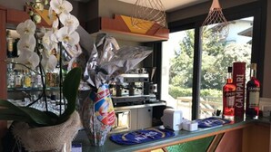A bar area with a view of the outdoors, a bottle of Campari, and a coffee machine. - Hotel Villa Rosa (Sirmione)