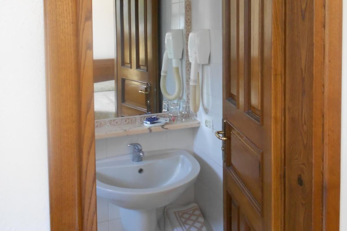 A bathroom with a wooden door, a sink, a mirror, and a towel rack.