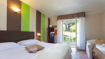 A hotel room with two beds, a green accent wall, and a view of the outdoor patio.