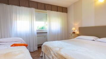 Habitación de hotel con dos camas, un escritorio y una ventana con cortinas.