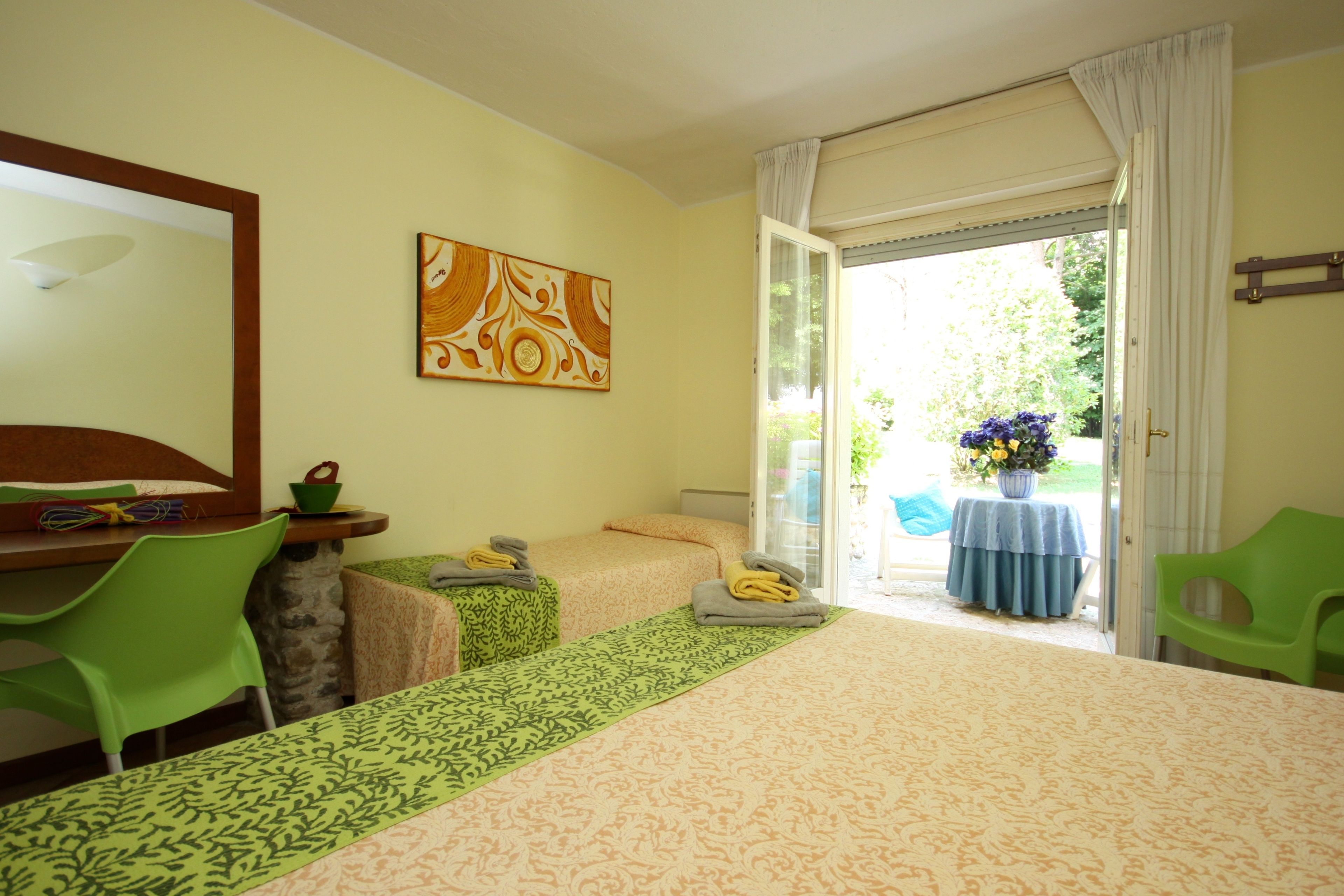 Une chambre d’hôtel avec deux lits, un bureau, des chaises, un tableau et une vue sur l’extérieur.