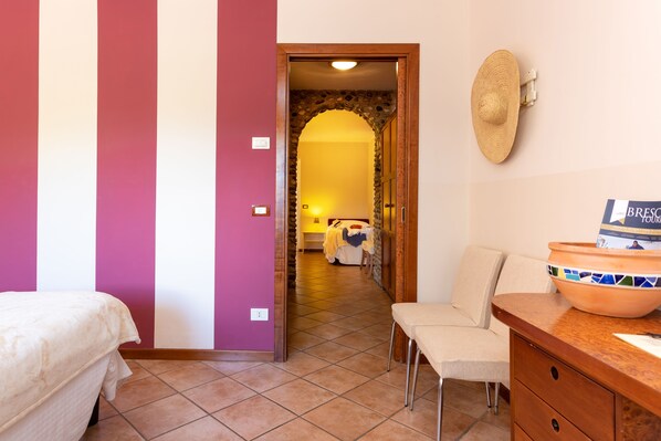 Habitación de hotel con cama, una silla, una mesa con un tazón y un sombrero colgado en la pared.