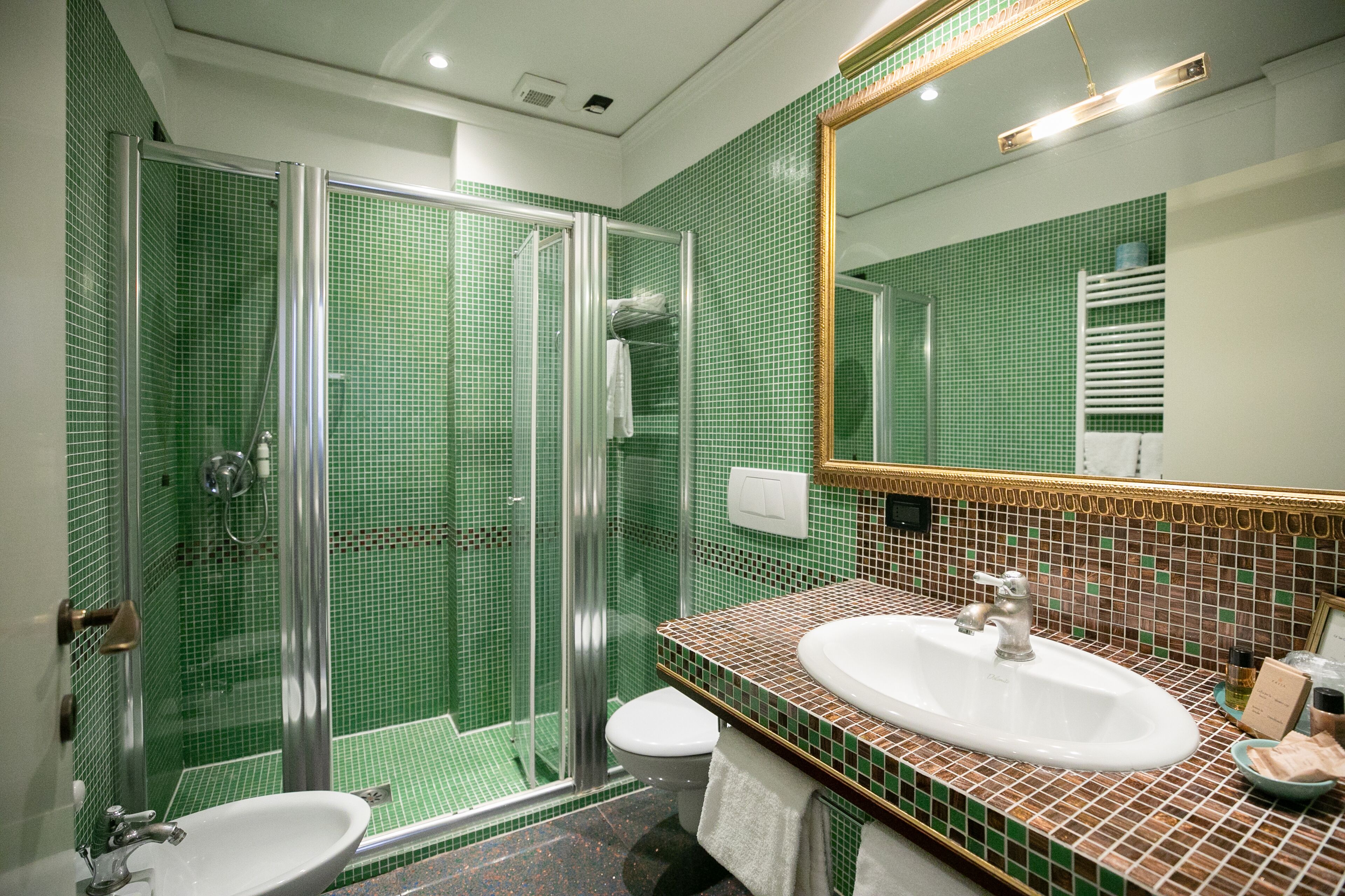 A bathroom with a glass-enclosed shower, a sink, and a toilet.