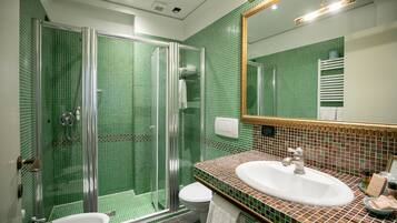 A bathroom with a glass-enclosed shower, a sink, and a toilet.