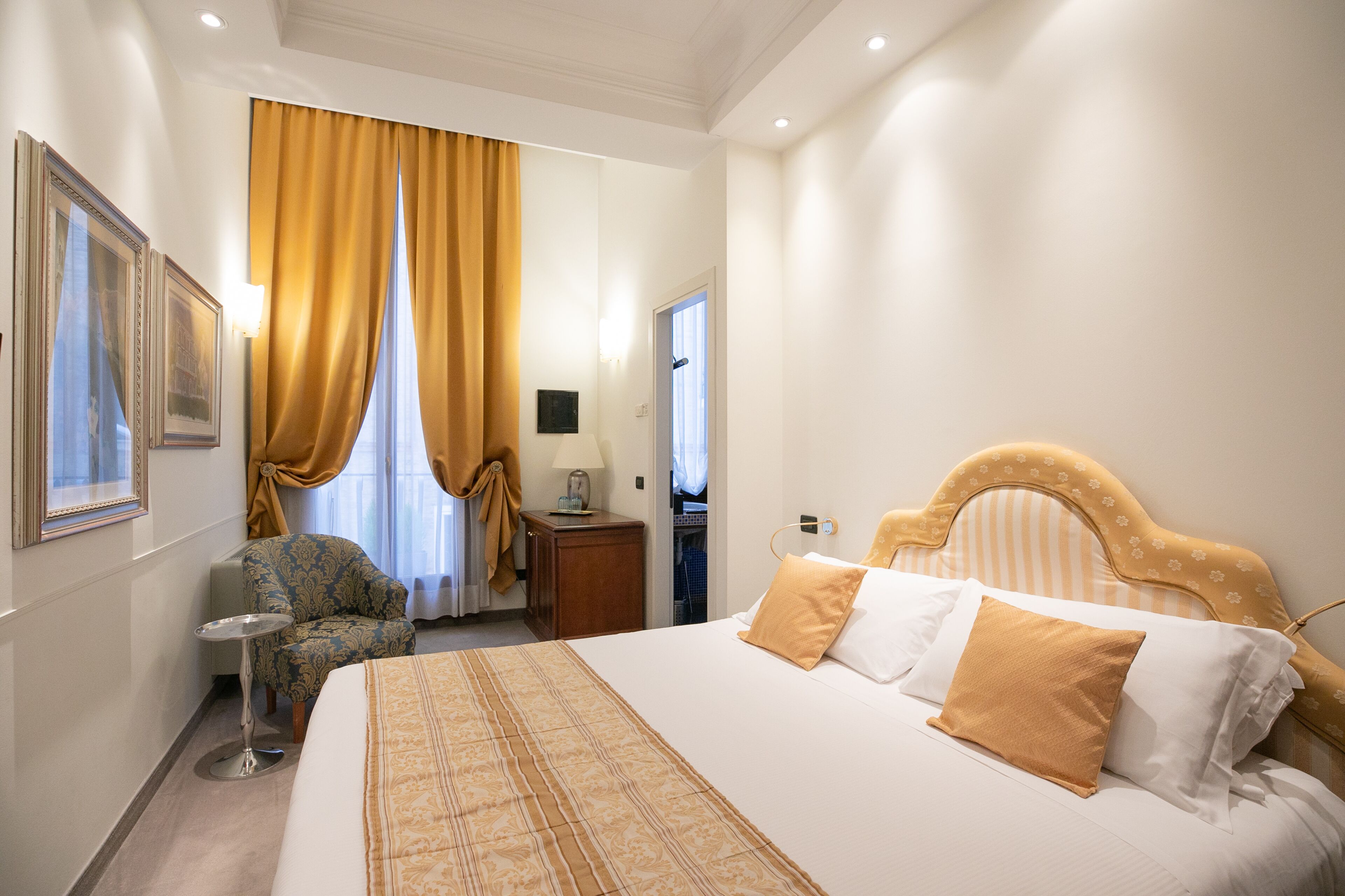 Une chambre d’hôtel avec un grand lit, une chaise, une petite table et une armoire.