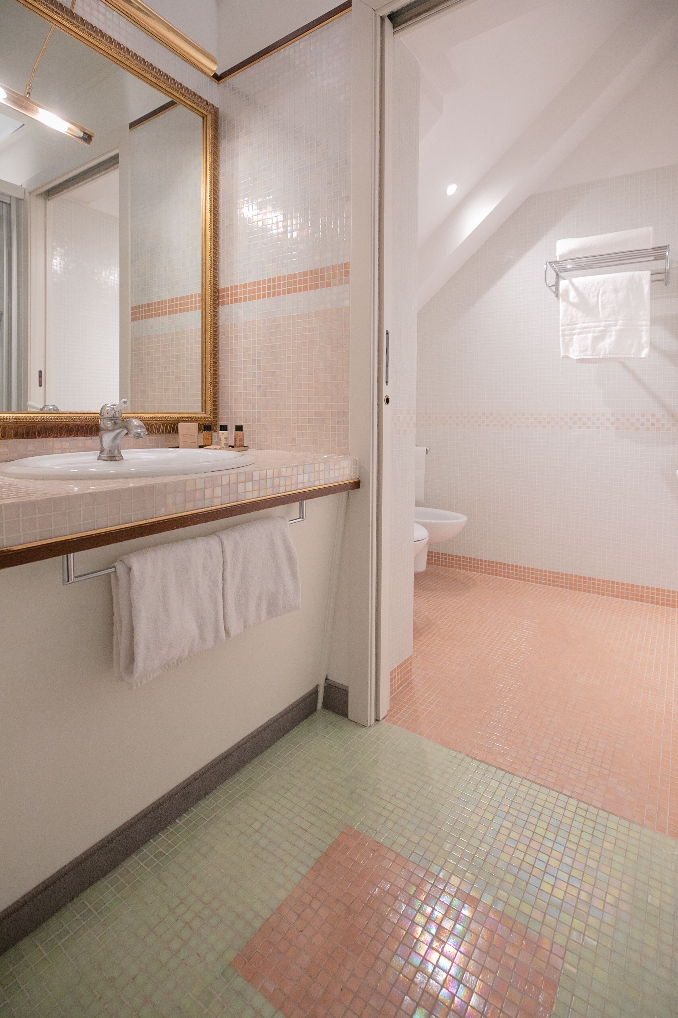 A bathroom with a white sink, a mirror, a towel rack, and a toilet.