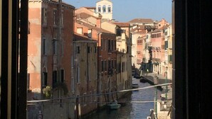 Un canal bordé de bâtiments des deux côtés, un pont et une tour qui se dessine au loin.