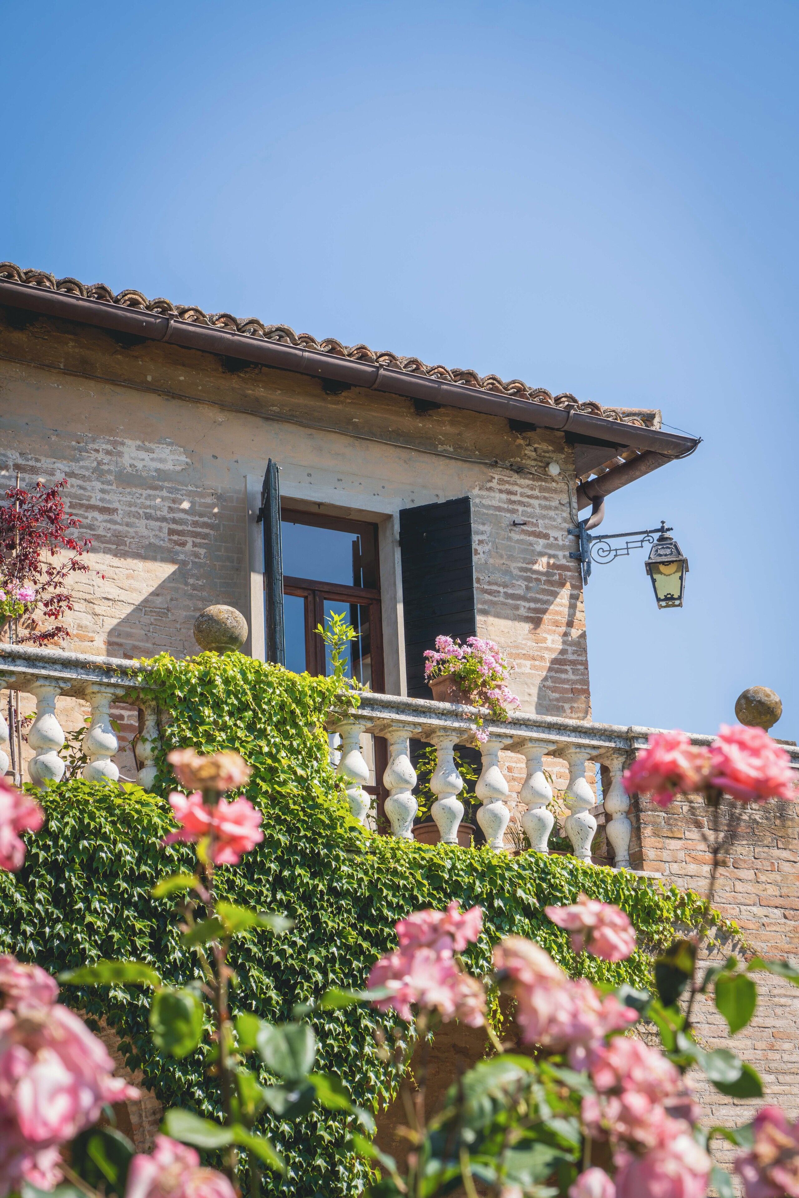 A traditional building with a stone facade, a balcony with a balustrade, and a clear blue sky.