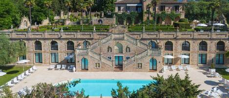 A large building with a swimming pool, multiple balconies, and a garden area.