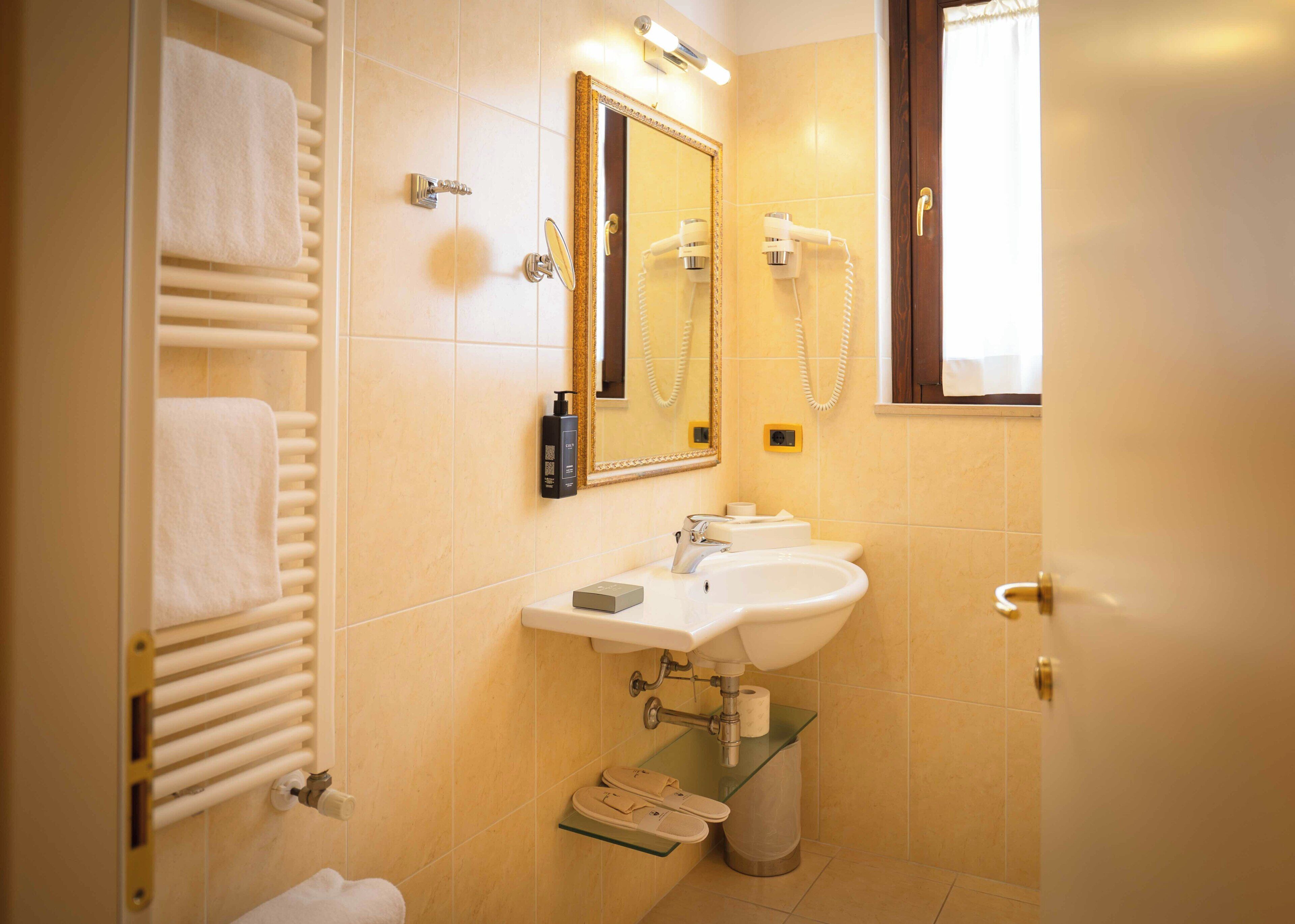 Ein Badezimmer mit Waschbecken, Spiegel, Handtuchhalter und Föhn.