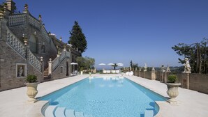 Una gran piscina con fachada de piedra y vistas a la ciudad.