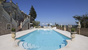 Una piscina al aire libre de temporada, sombrillas