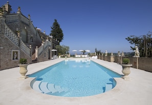 Una gran piscina con fachada de piedra y vistas a la ciudad.