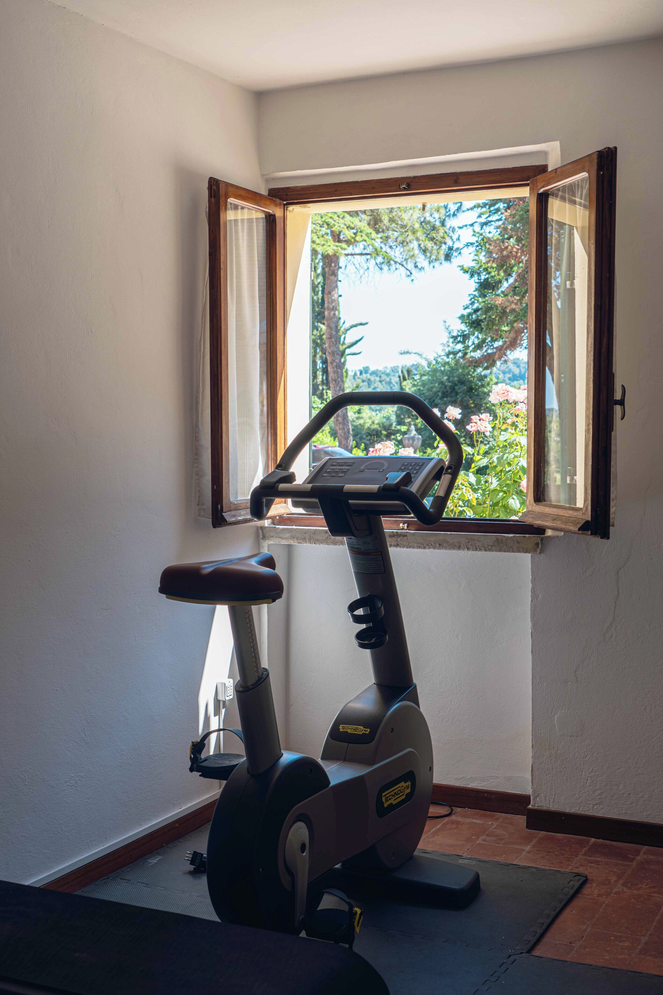 Uma bicicleta ergométrica numa sala com janela, porta e parede.