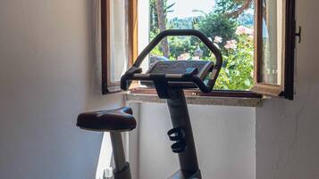Uma bicicleta ergométrica numa sala com janela, porta e parede.