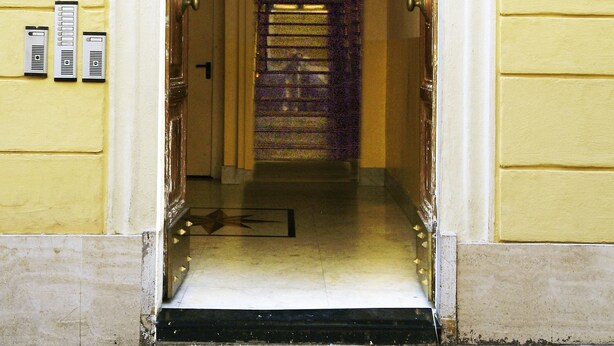 L’entrée de l’hôtel Meridiana se distingue par son portail classique en arc de cercle, un piano situé au deuxième étage et une enseigne indiquant le nom et l’adresse de l’hôtel.