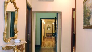 Un couloir doté d’un sol à motifs, d’un grand miroir et de luminaires fixés au mur.