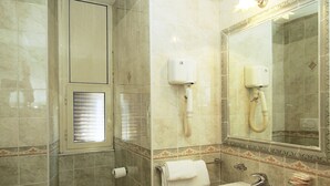 Une salle de bain équipée de toilettes, d’un bidet, d’un lavabo et d’un miroir.