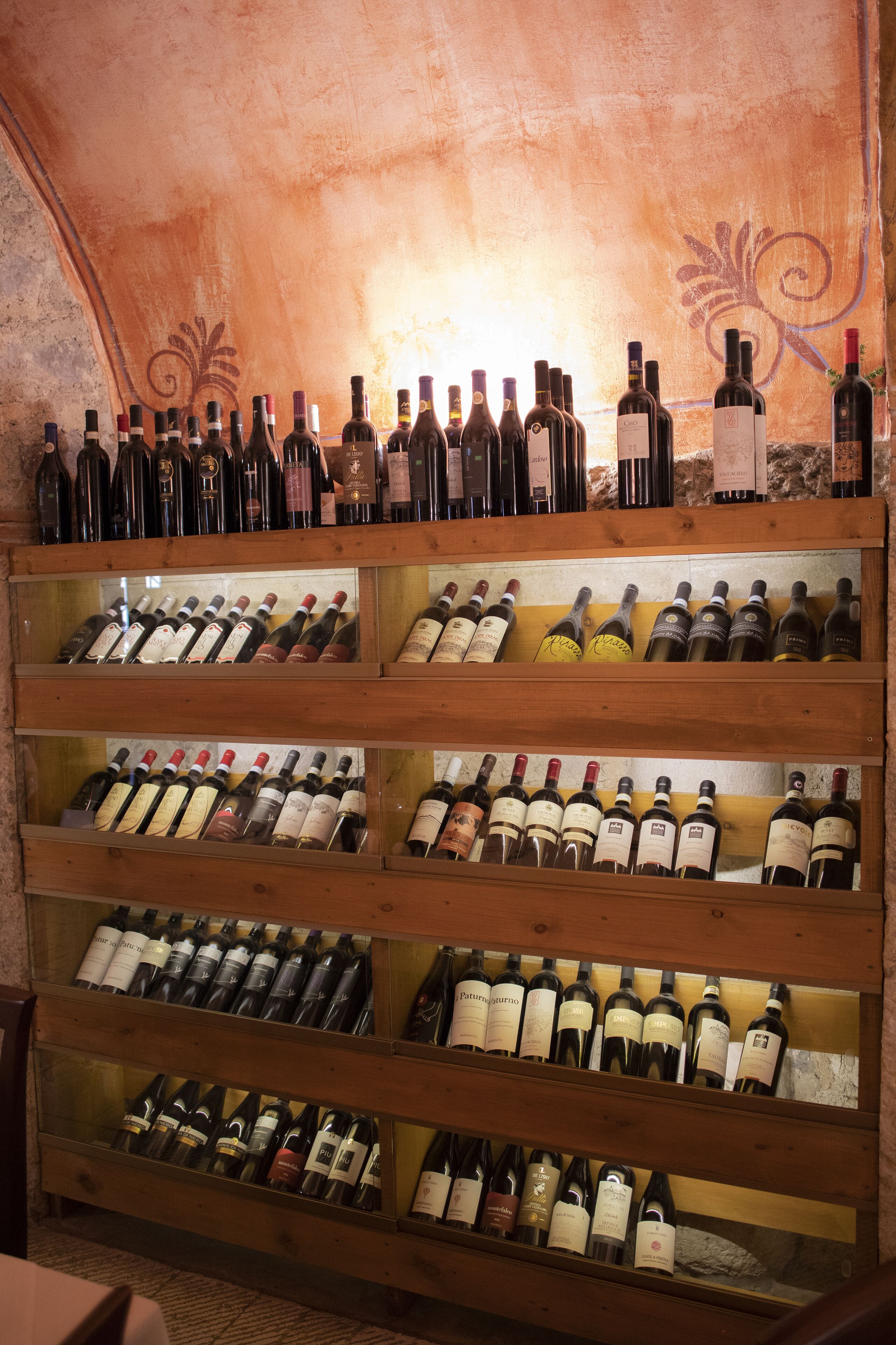 A wine cellar with multiple wooden shelves holding various bottles of wine.