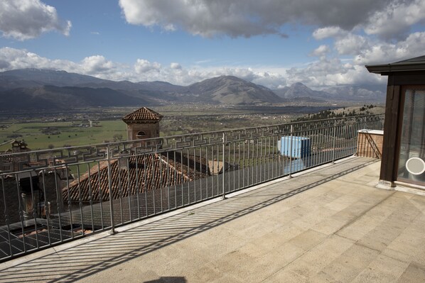 A balcony with a metal railing overlooking a valley, mountains, and a distant town. - Villa Cosilinum (Padula)
