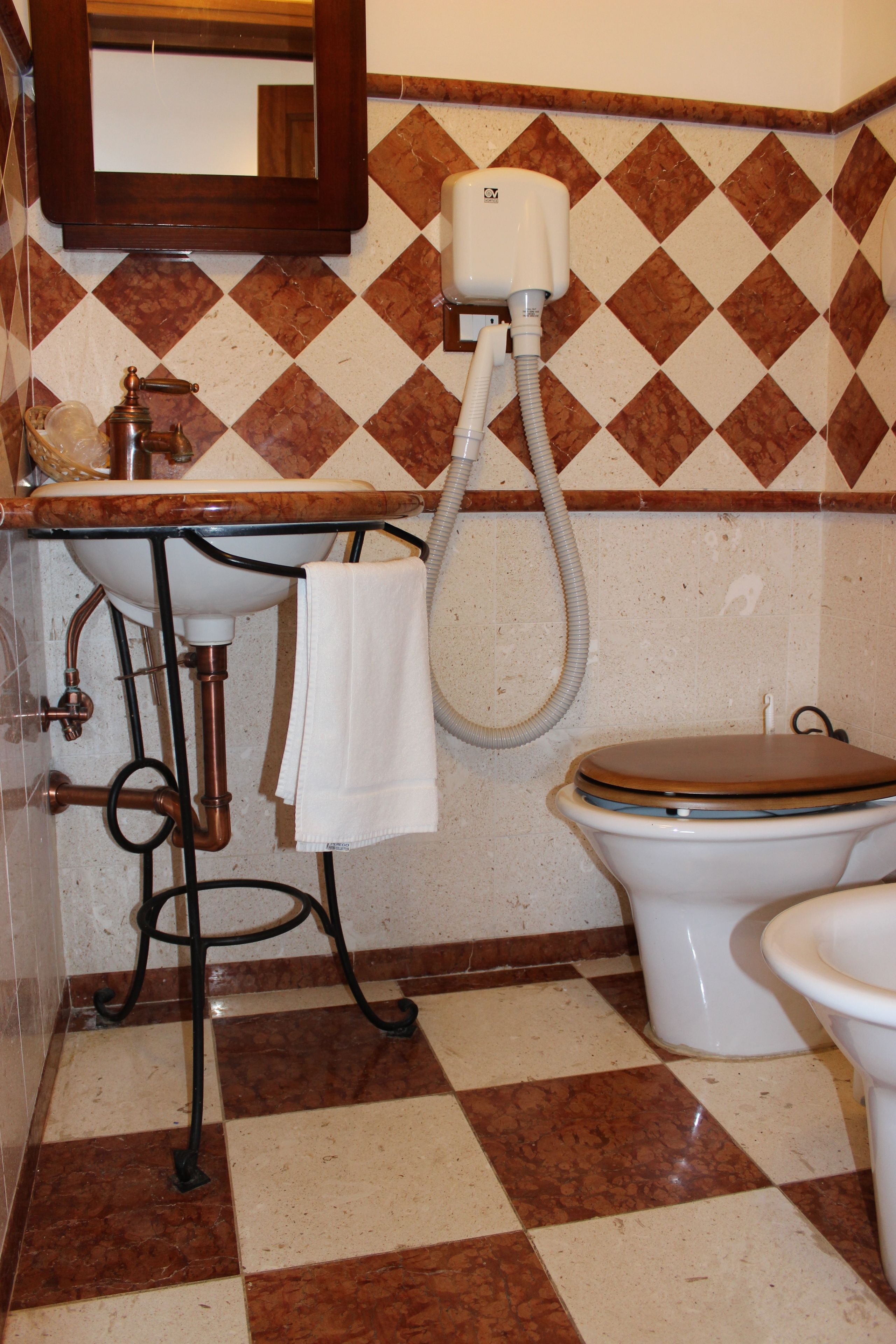 A bathroom with a checkered floor, a sink, a toilet, and a mirror.