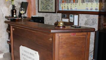 A wooden reception desk with a plaque, a framed menu, and a wall-mounted telephone.