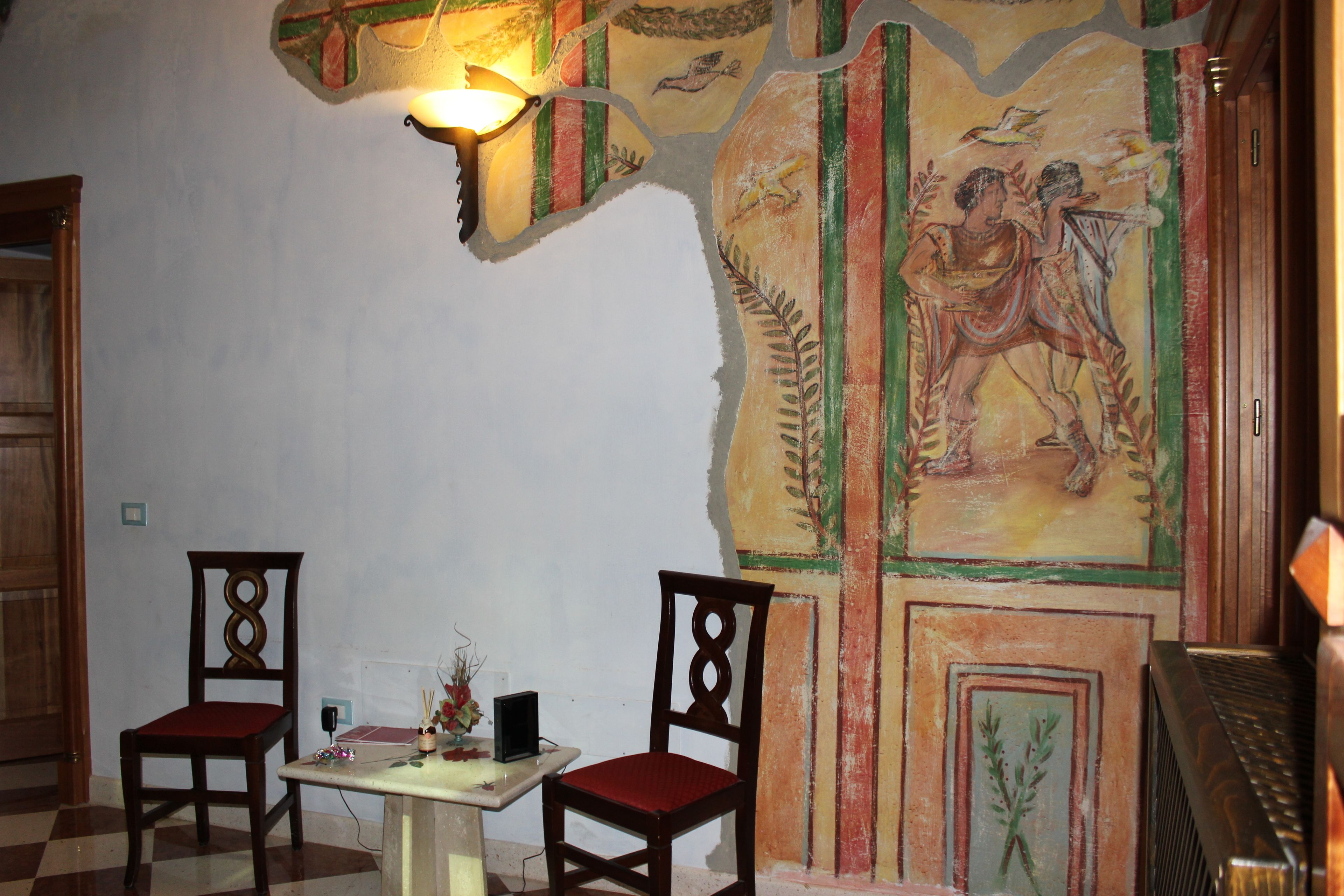 Una habitación con dos sillas de madera, una mesita y una pared decorada con un mural.