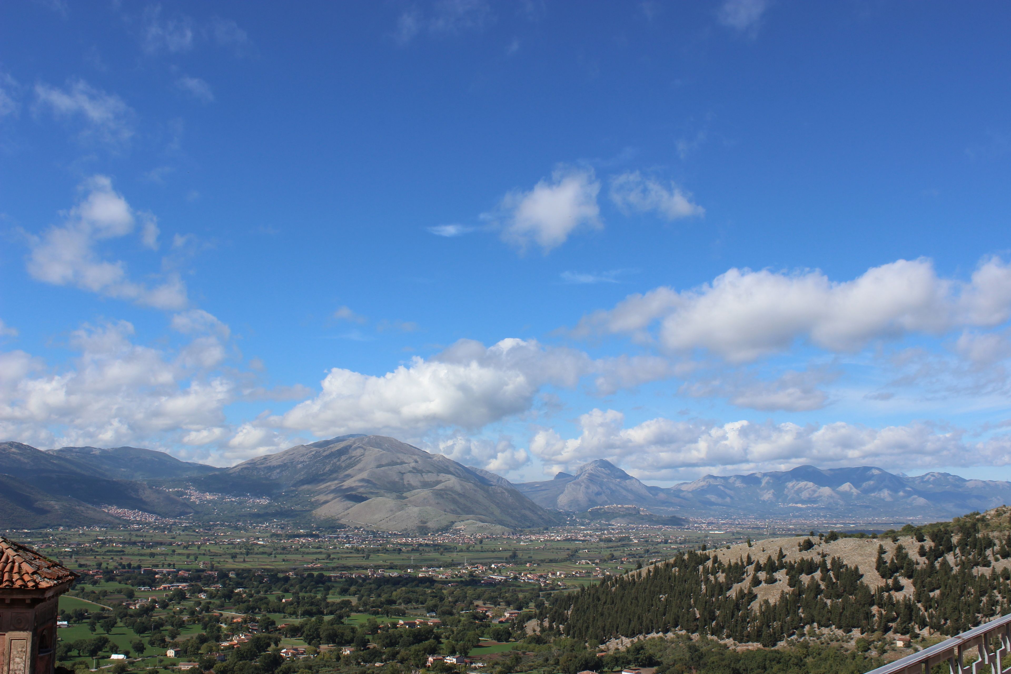 A mountainous landscape with a village in the valley, a clear sky, and a prominent mountain in the background.