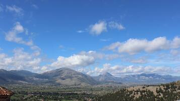 A mountainous landscape with a village in the valley, a clear sky, and a prominent mountain in the background.