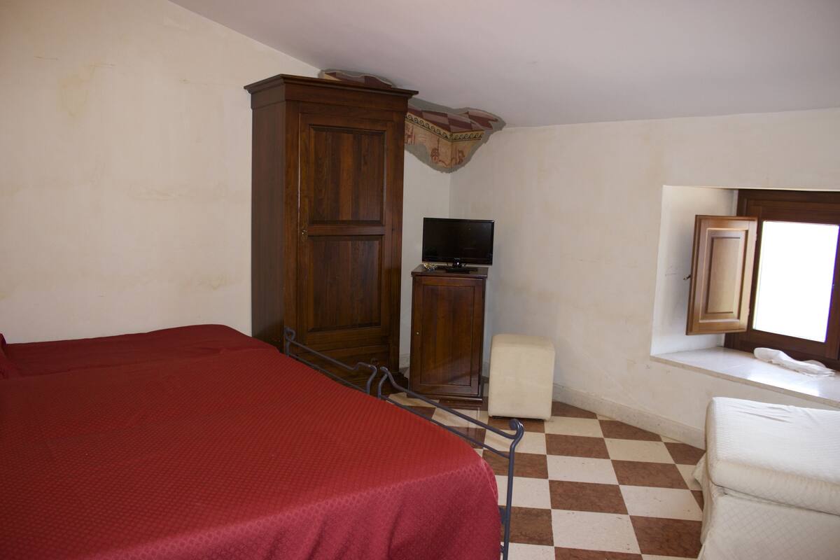 A room with a bed, a television, a cabinet, and a window.