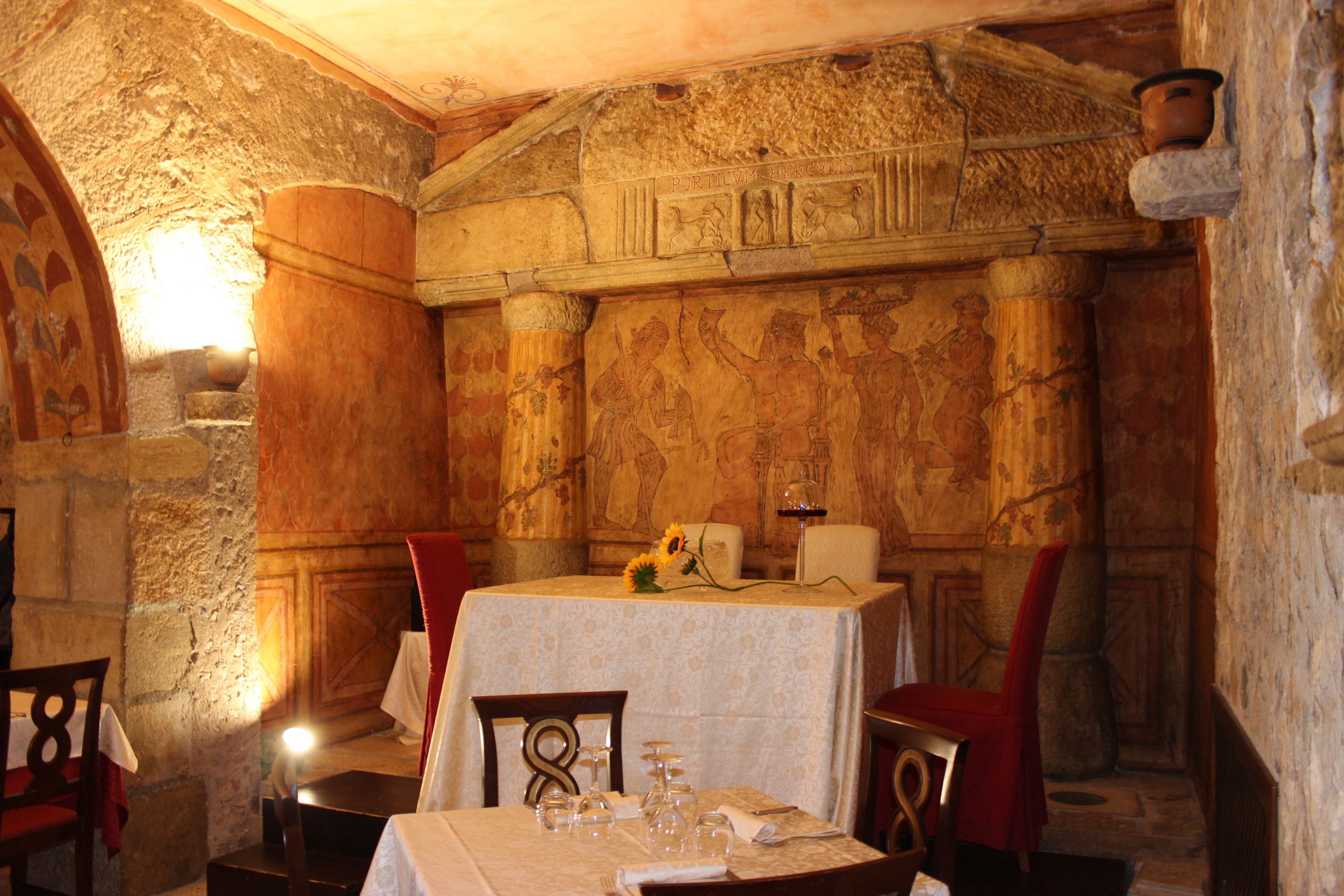 A dining room with stone walls, a table set with glassware, and red chairs.