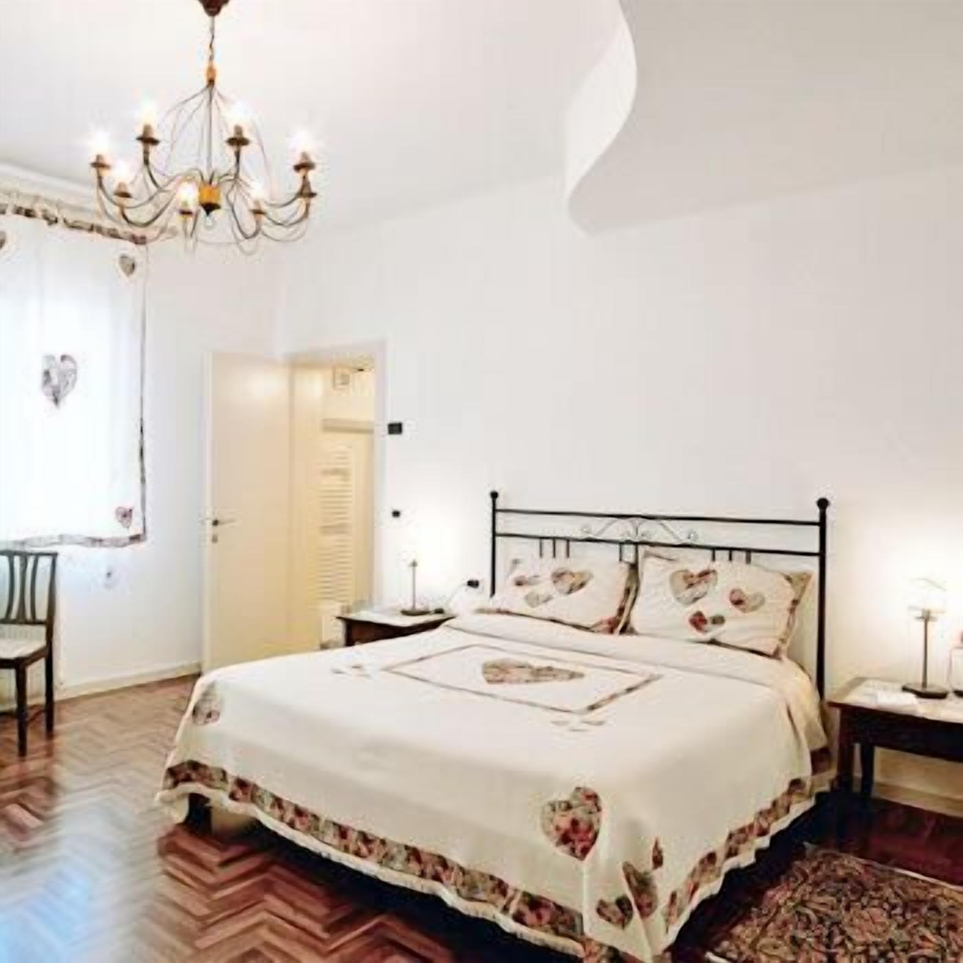 A bedroom with a bed, a chandelier, a chair, and a door.